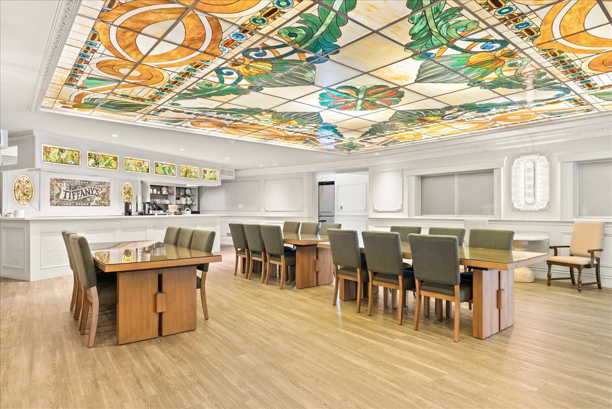 The dining hall at Rodman Hall, with long shared tables beneath a large stained-glass ceiling