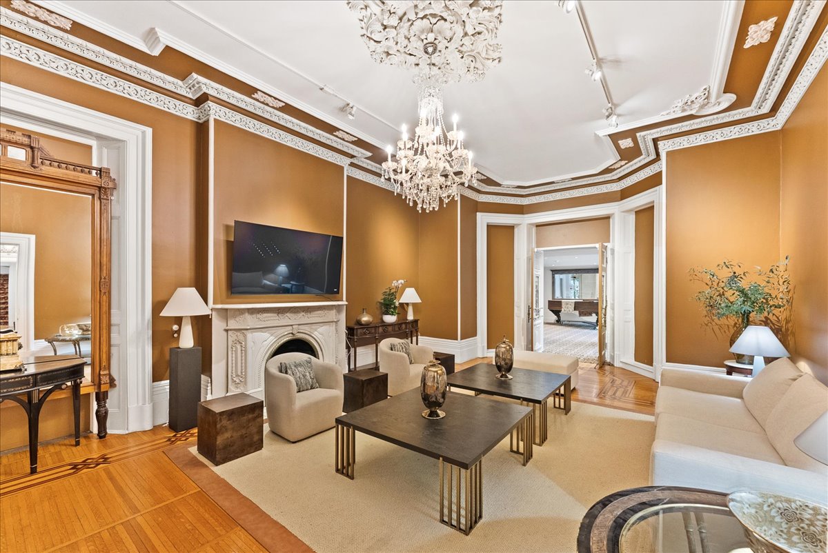 A drawing room at Rodman Hall with a marble fireplace, chandelier and soft seating