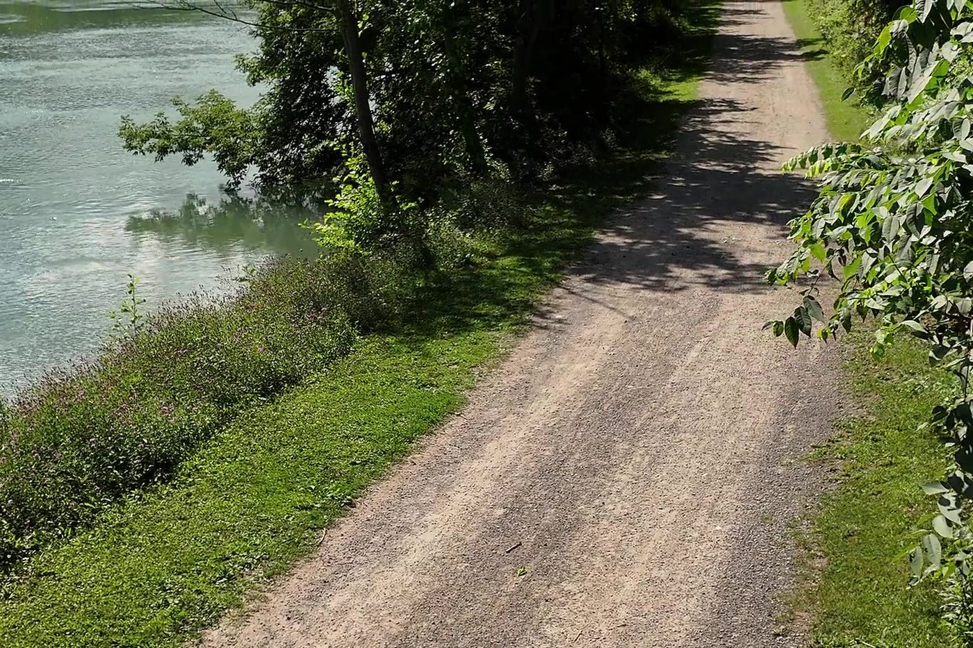 A gravel path following the bank of the Twelve Mile Creek beneath mature trees