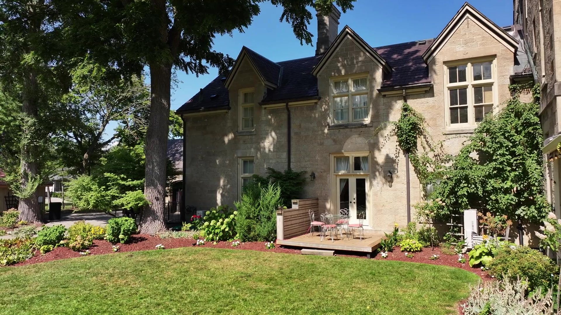 The Twelve Mile Recovery residence, a limestone house with ivy and garden beds beneath mature trees